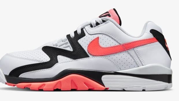 Side view of a white, orange, and black Nike shoe.
